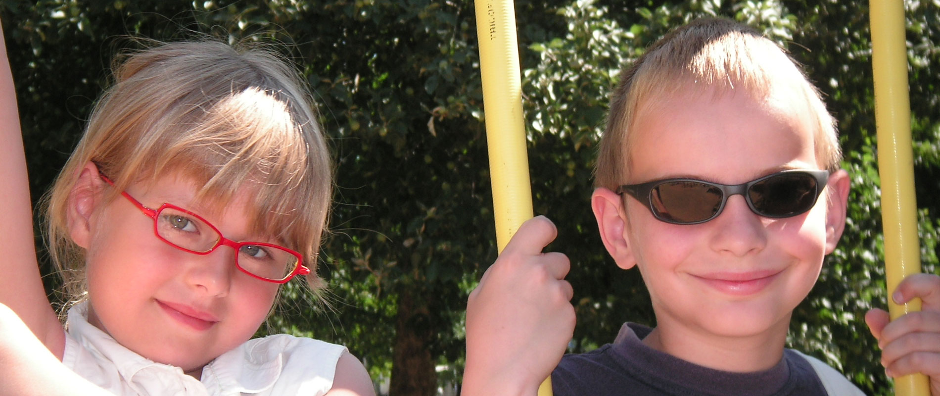 Kinder mit Brille auf einer Schaukel