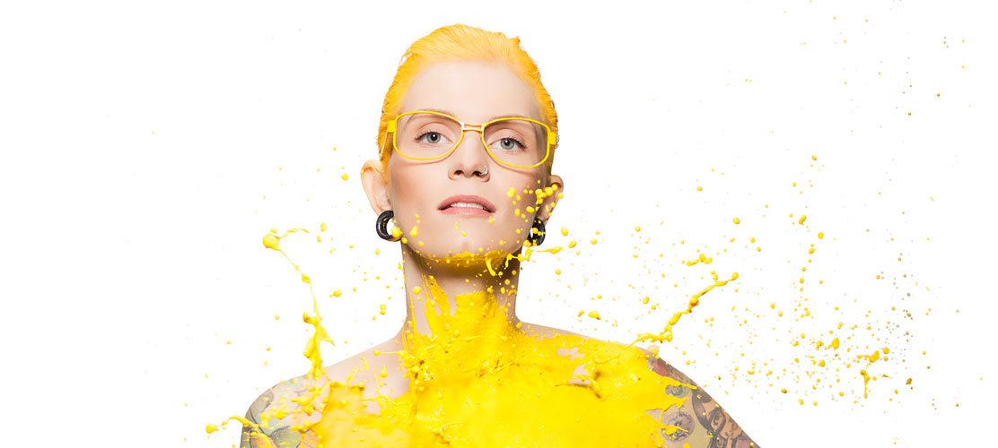 Frau mit gelber Brille wird mit gelber Farbe bekleckert
